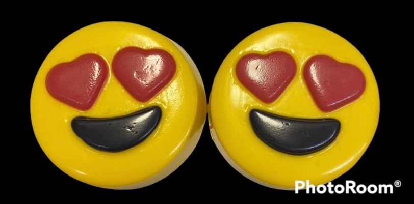 Two yellow heart-eyes smiley candies with red hearts and black smiles