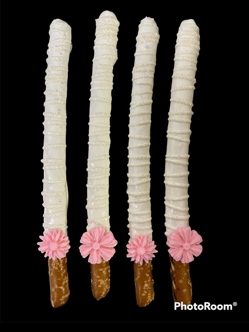 Six decorated candy sticks in brown, white, and peach on a black background