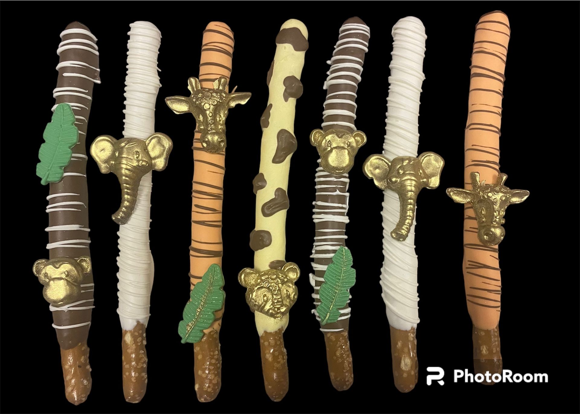 Six decorated candy sticks in brown, white, and peach on a black background