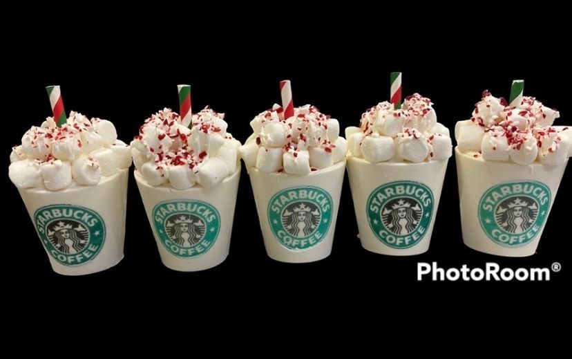 Five Starbucks cups of whipped cream topped holiday drinks with crushed candy canes on a black background