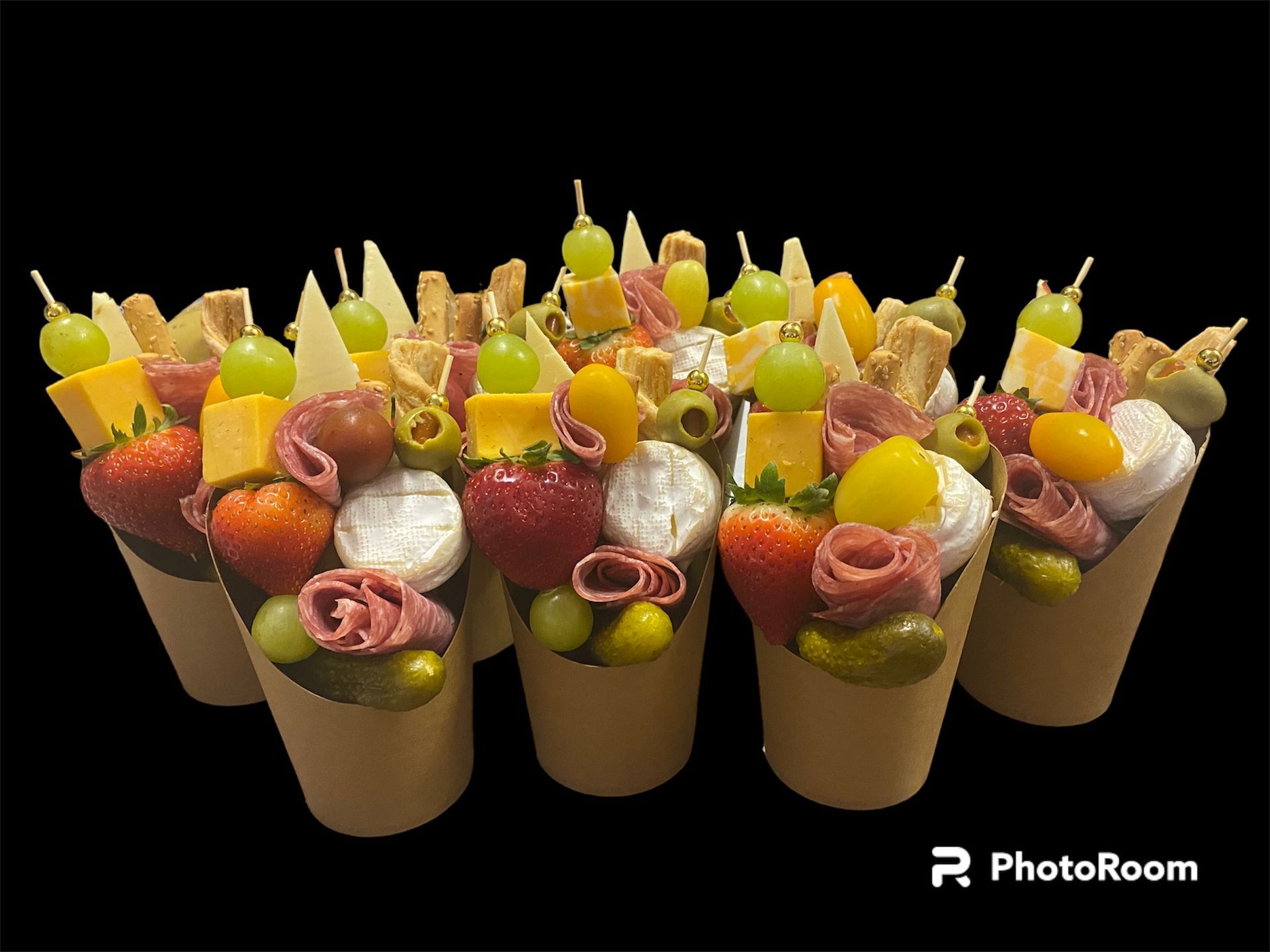Round charcuterie board with meats, cheeses, crackers, olives, and fruit arranged in a spiral pattern.