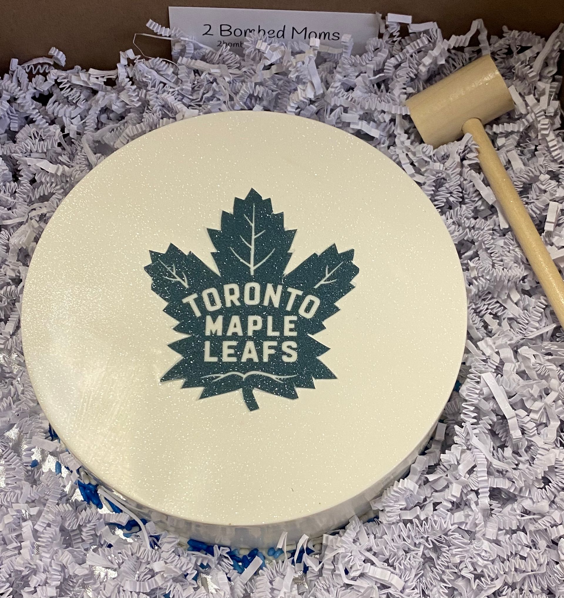 Toronto Maple Leafs round cream-colored sign with dark green logo, surrounded by shredded paper packaging