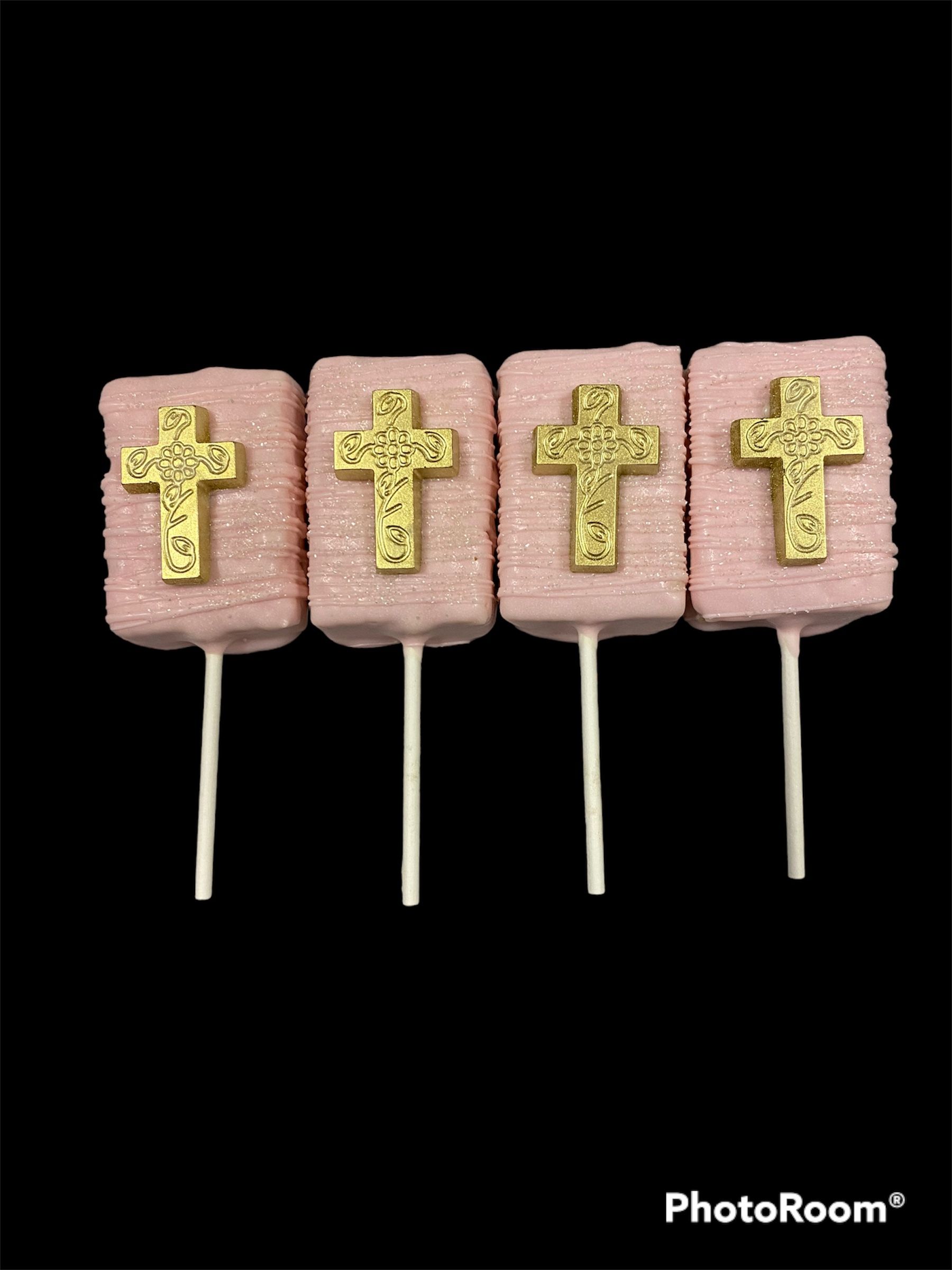 Four pink popsicles with gold crosses on sticks against a black background