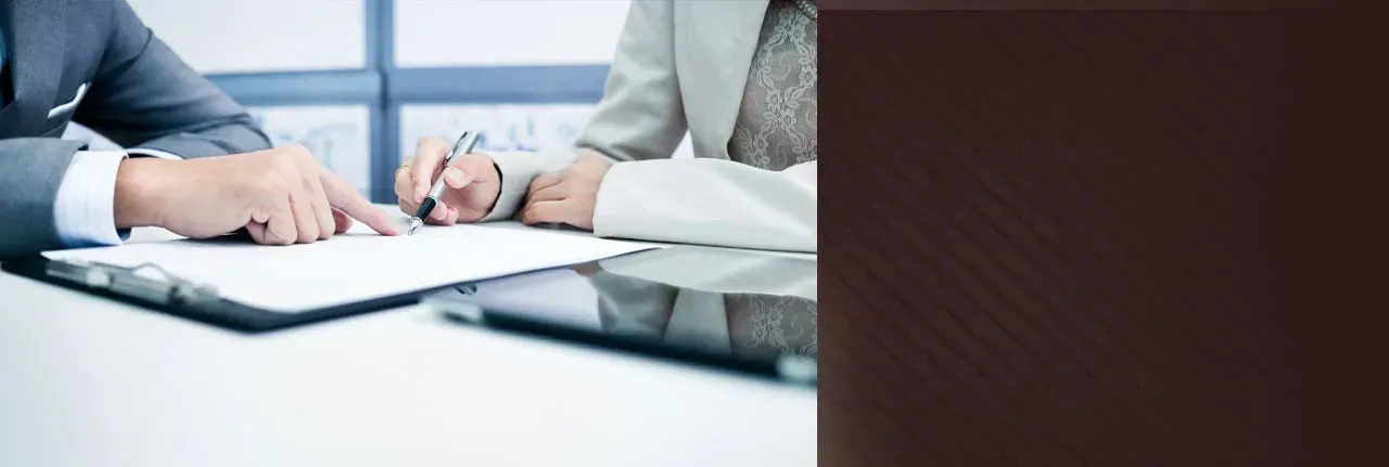 A man and a woman are sitting at a table signing a document.