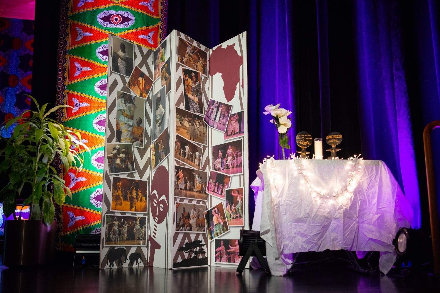 Stage set with photos, Africa map, purple lighting, white table, awards, and patterned backdrop.