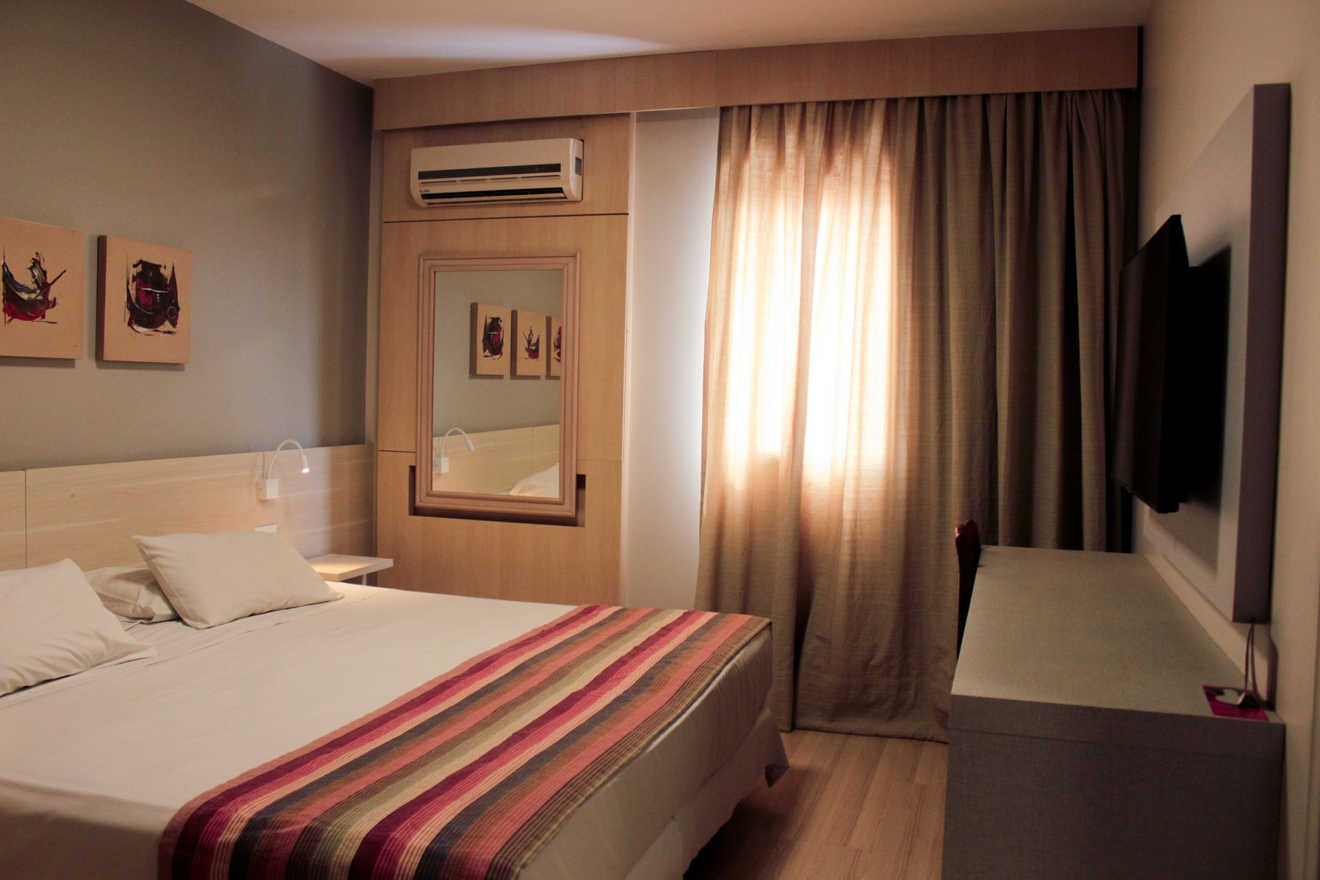 Um quarto de hotel com uma cama king size e uma TV de tela plana