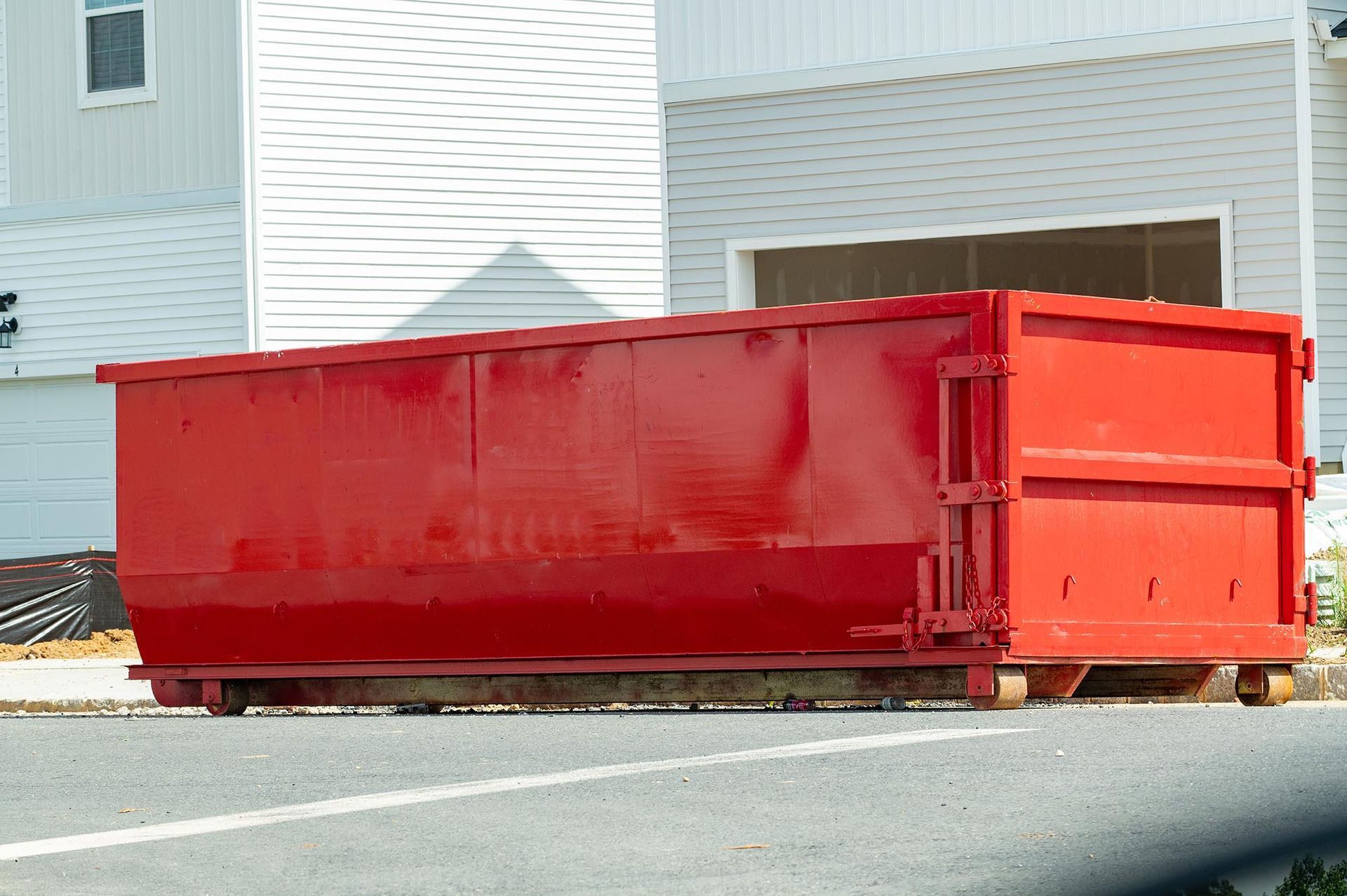 Red construction dumpster beside a building and parking lot