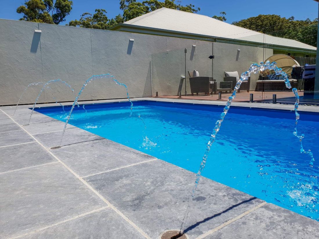 A Swimming Pool With a Fountain in the Middle of It — Clarence Valley Pools In Woolgoolga, NSW