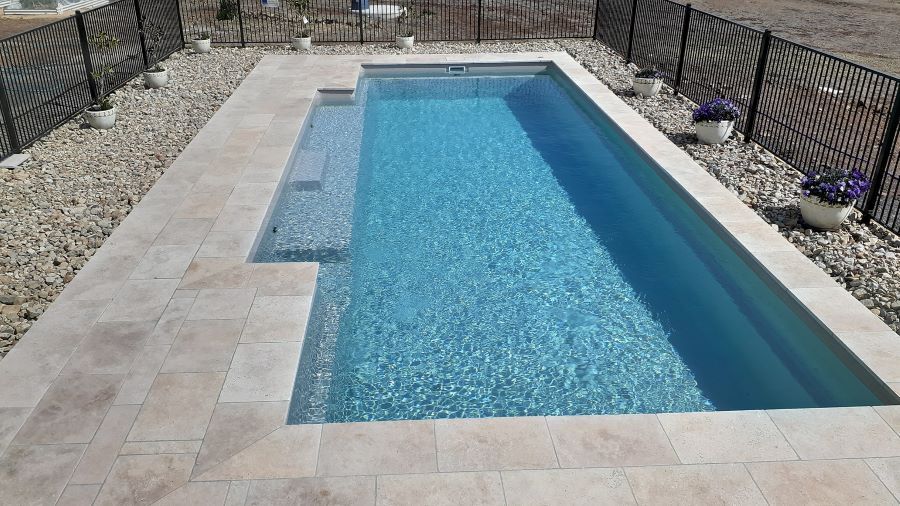 A Large Swimming Pool Surrounded by Black Fence — Clarence Valley Pools In Coffs Harbour, NSW