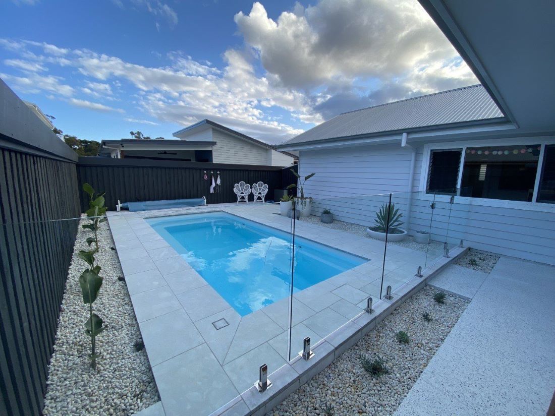 A Large Swimming Pool is Surrounded by Chairs and a Table — Clarence Valley Pools In Yamba, NSW