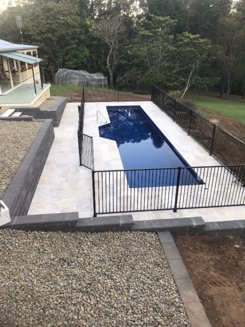 A Large Swimming Pool With a Black Fence Around It — Clarence Valley Pools In Yamba, NSW