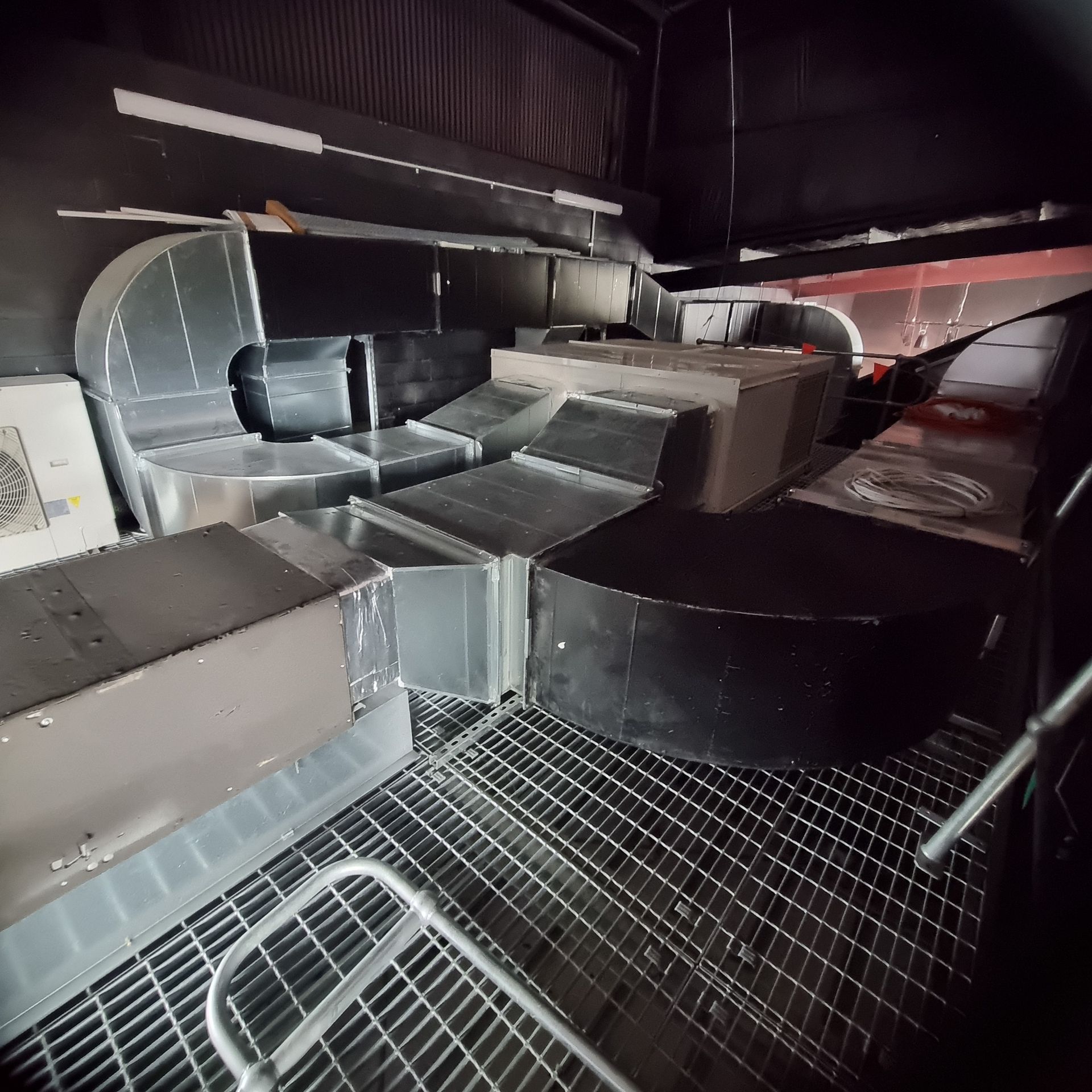 Industrial HVAC ductwork and metal vents inside a dark mechanical room