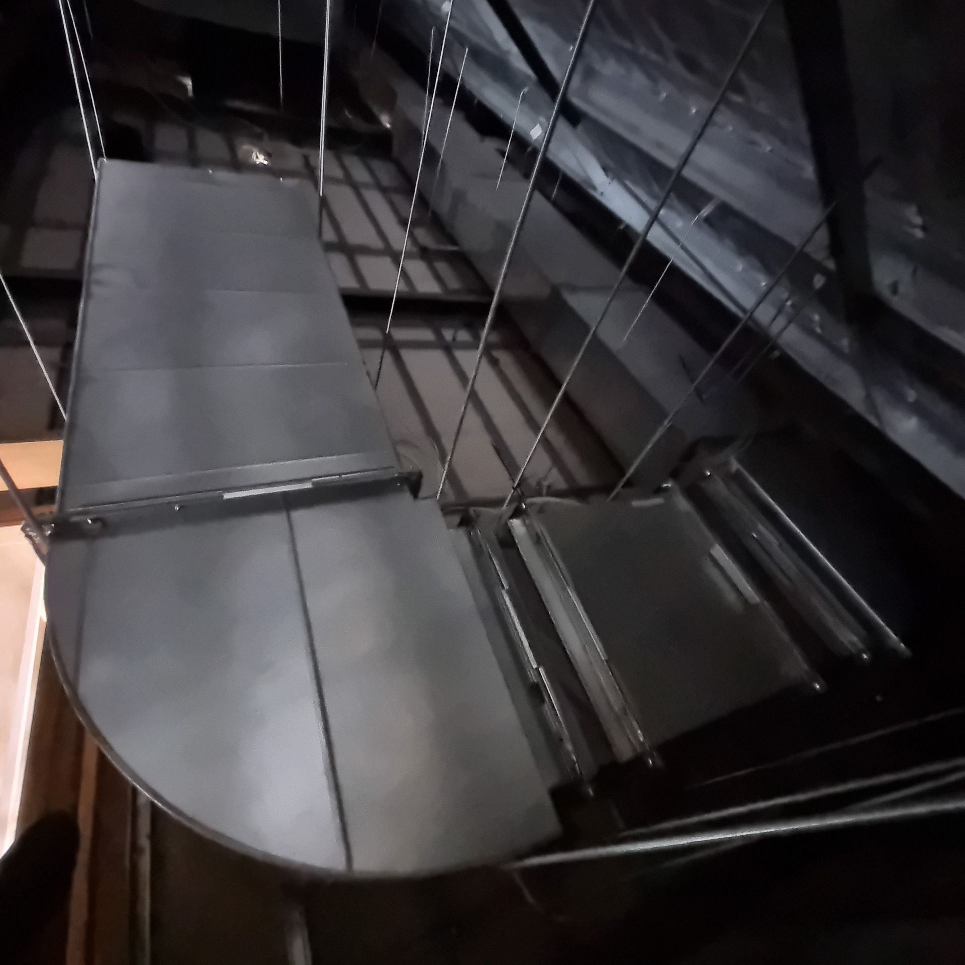 Dark industrial catwalk with metal stairs and railings in a dimly lit interior