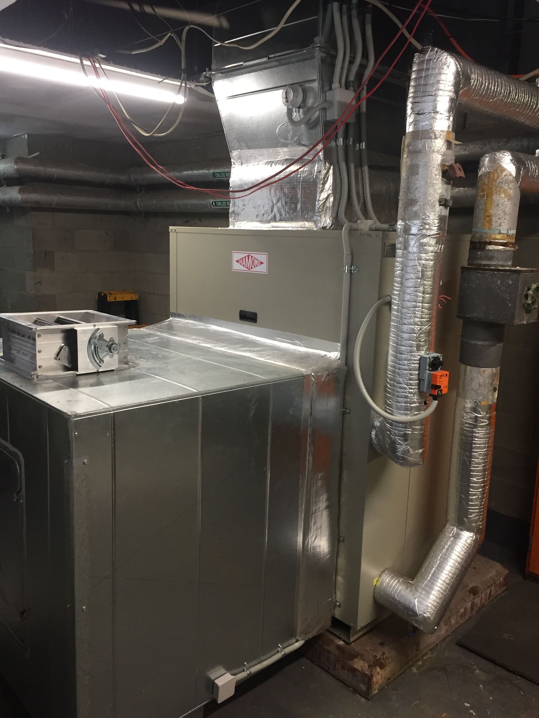 Basement HVAC equipment with metal ductwork and insulated pipes in a mechanical room