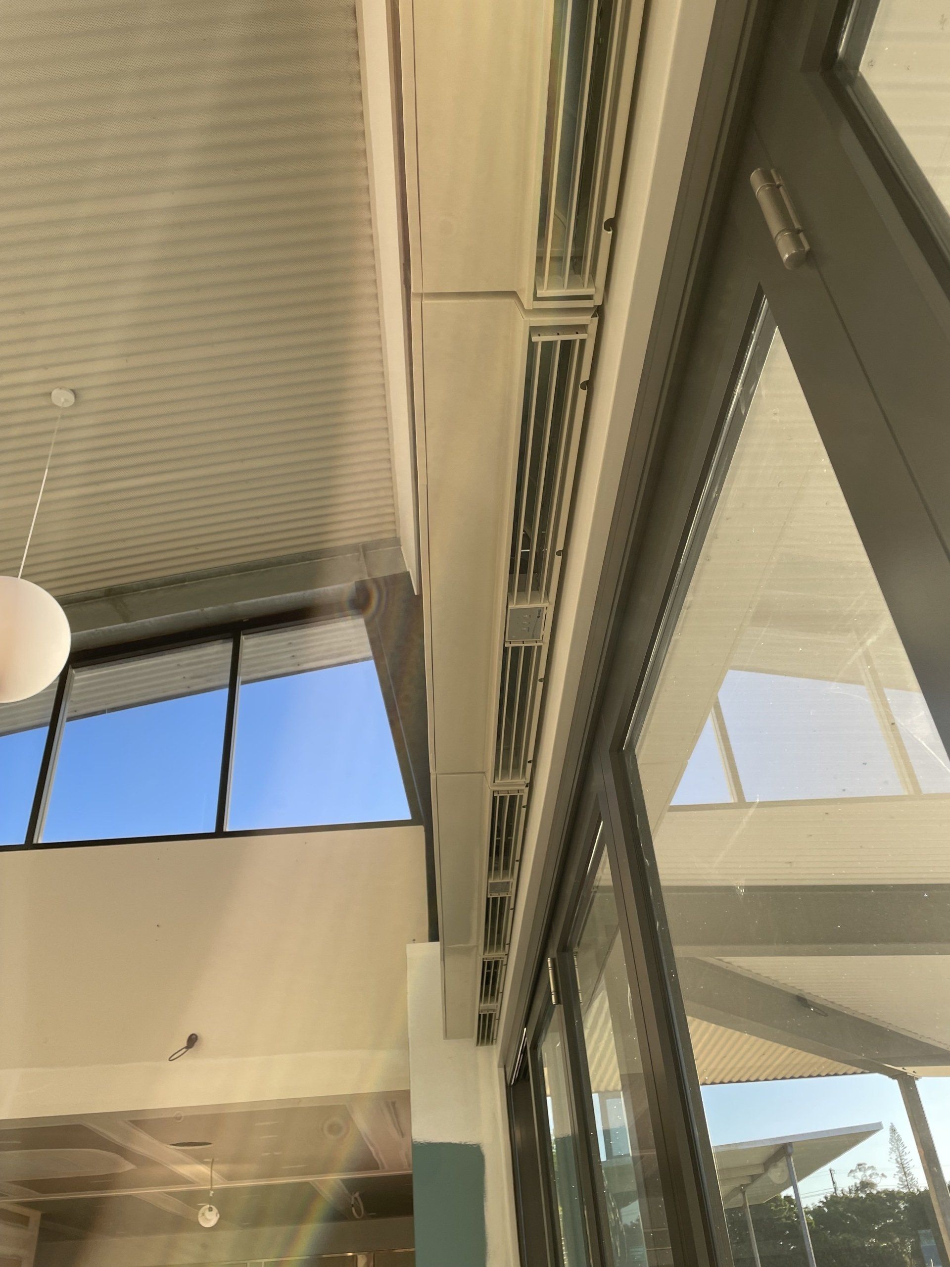 Interior view of a modern atrium with large windows, blinds, and mirrored glass walls
