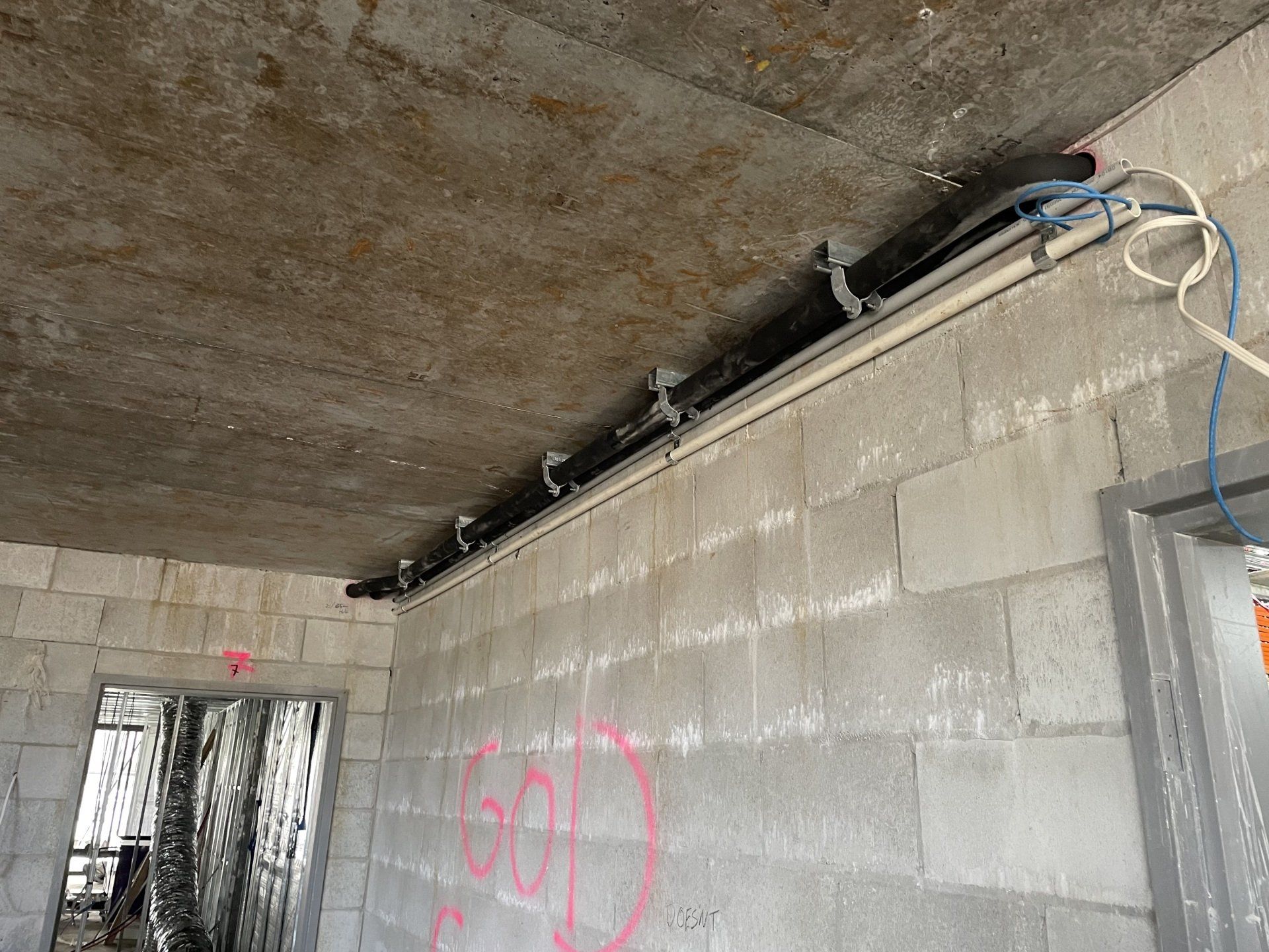 Concrete block wall with exposed wiring along a ceiling in an unfinished room