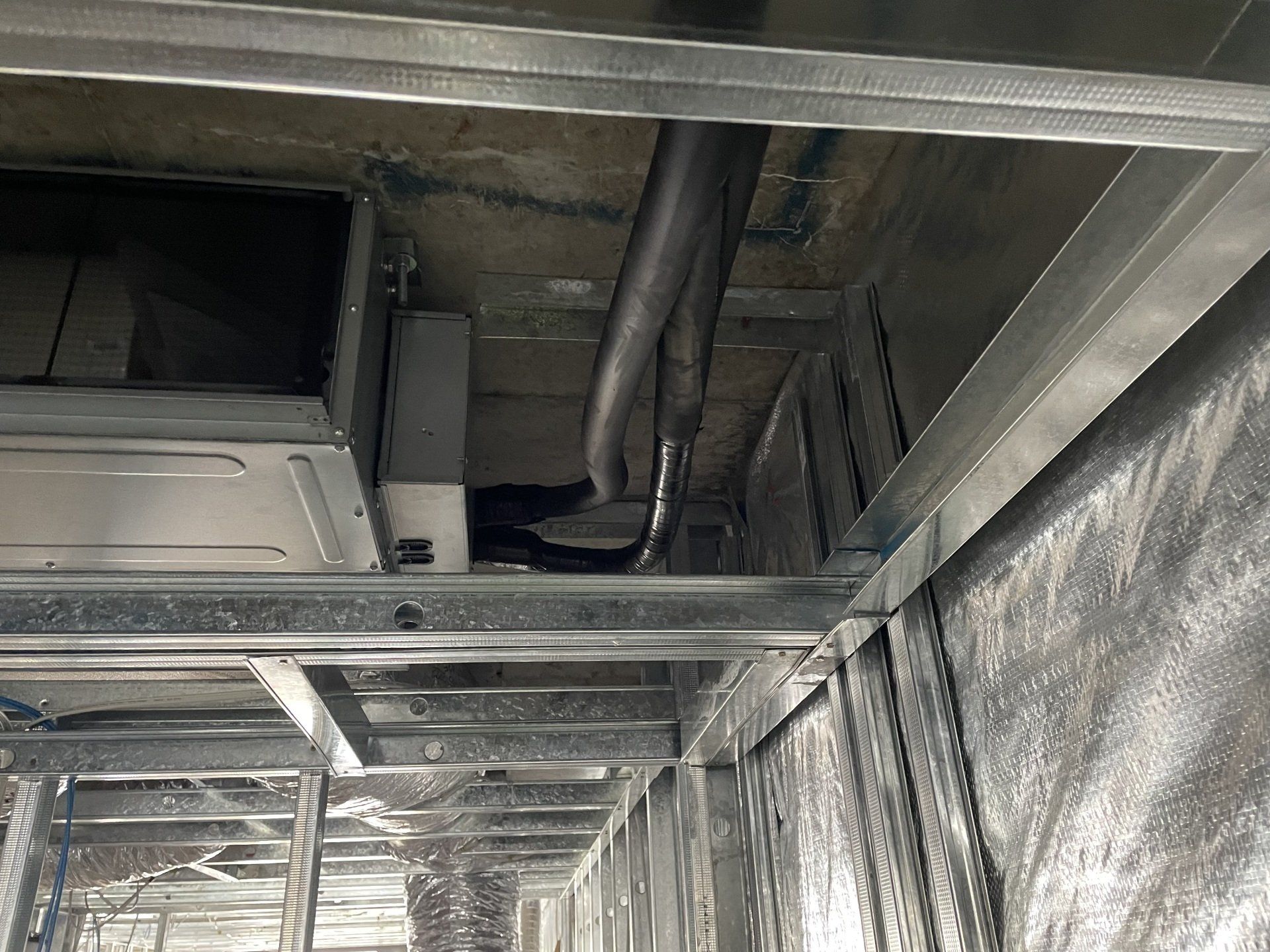 Exposed metal framing and ductwork in an unfinished ceiling space
