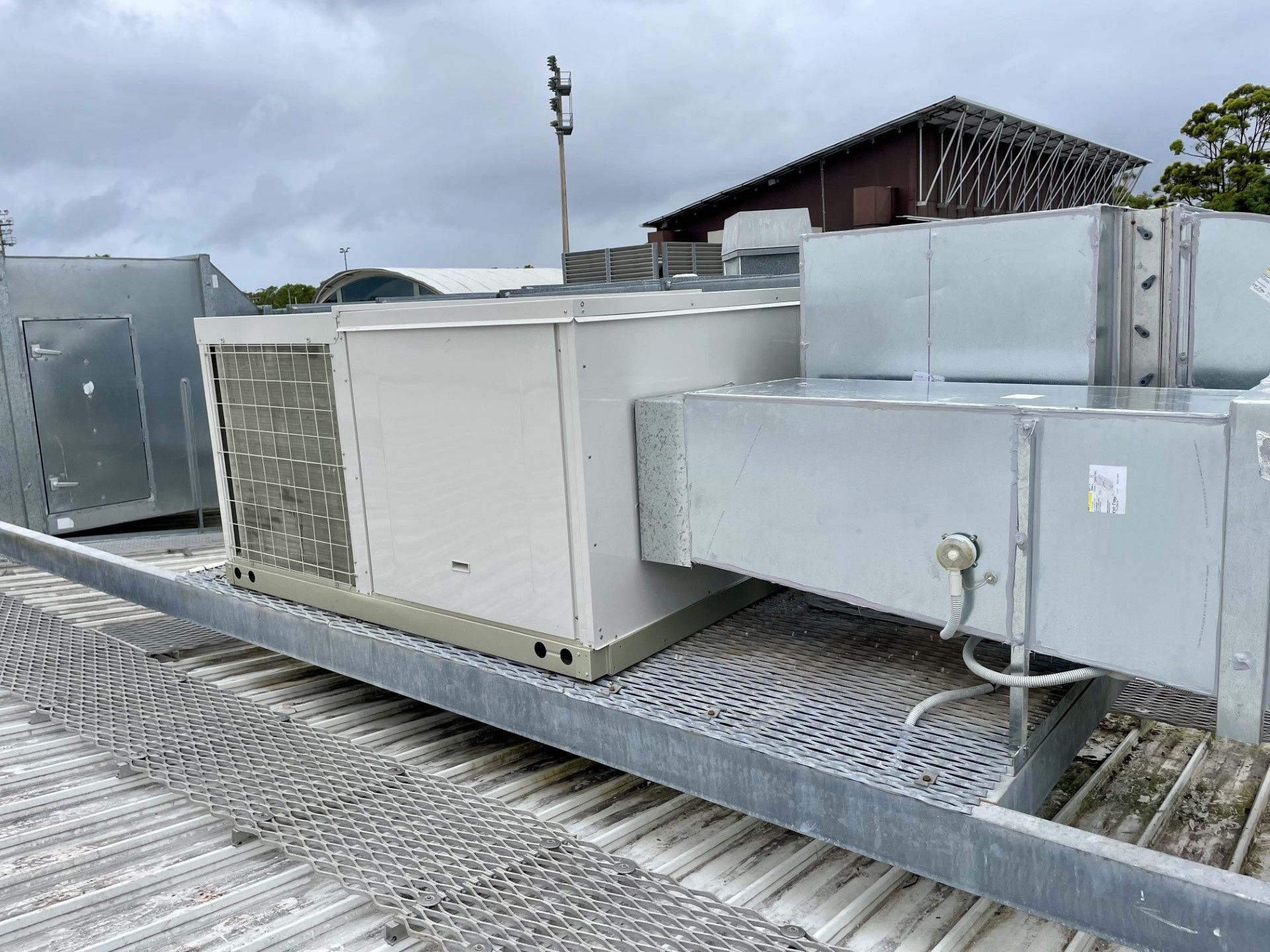 HVAC rooftop units on a metal platform under a cloudy sky