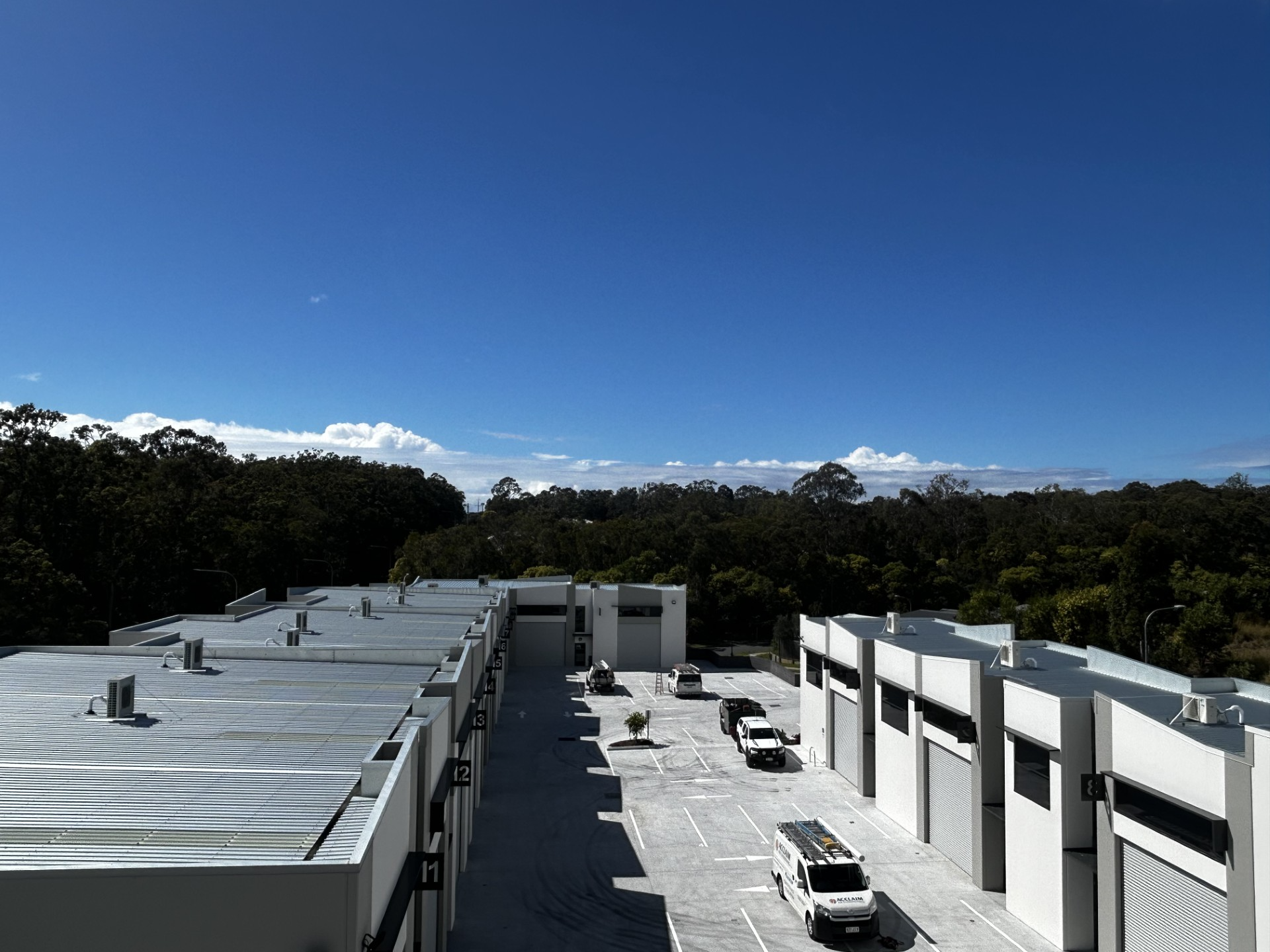 Rooftop with white buildings under a clear blue sky, with trees and mountains in the distance