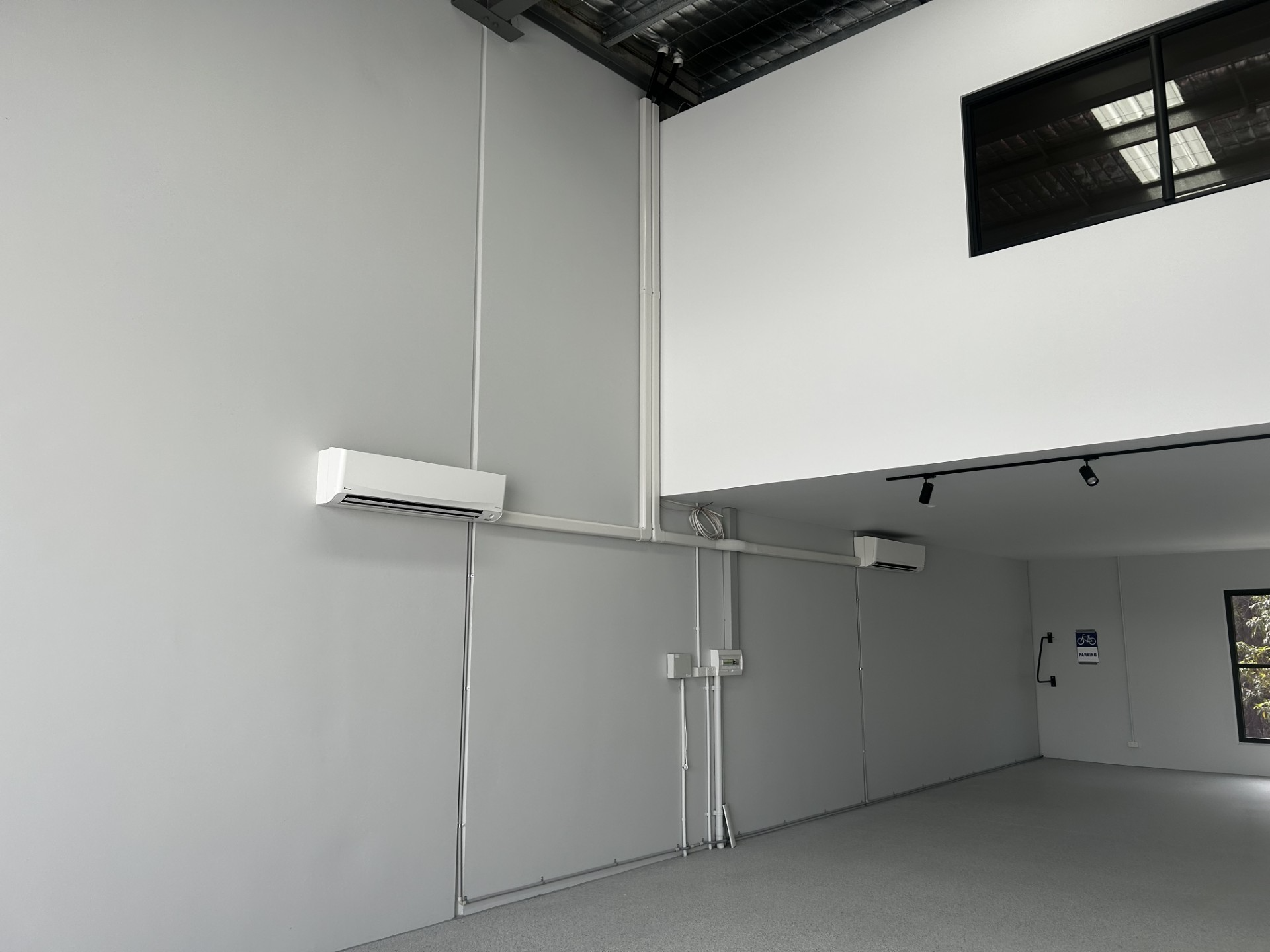Empty industrial interior with gray walls, high ceiling, and overhead windows