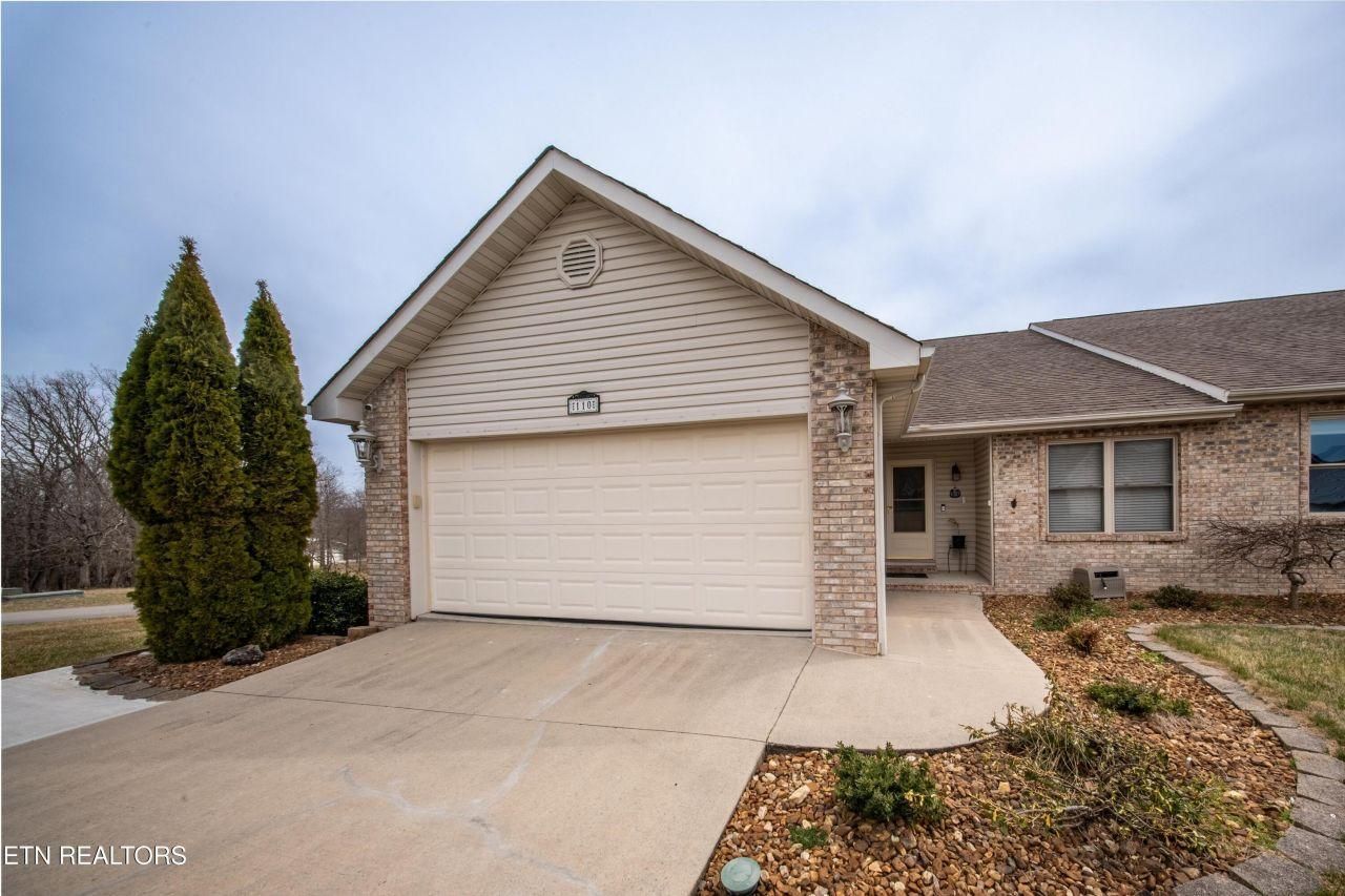 A house with a white garage door and a brick wall