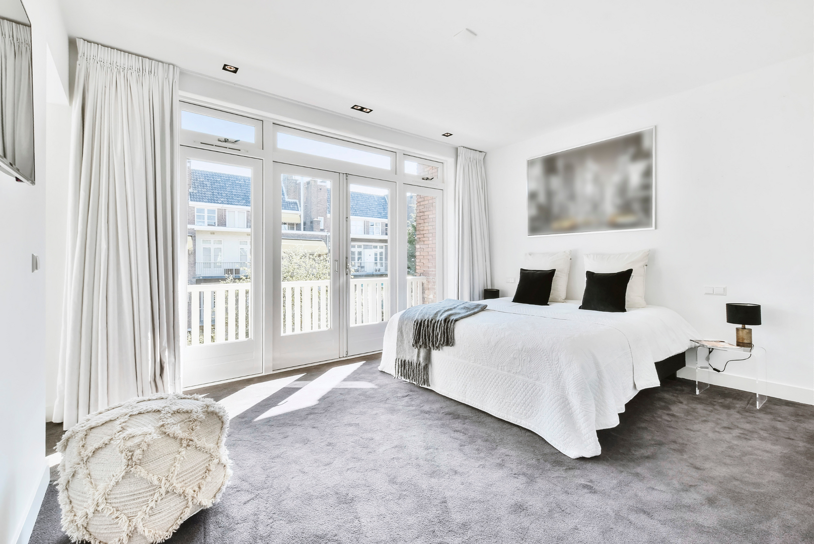 A bedroom with a large bed and a balcony.