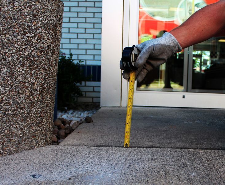 A person measuring a concrete surface with a tape measure