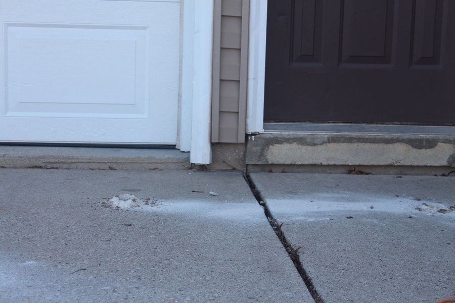 A white door and a brown door are next to each other on a sidewalk.