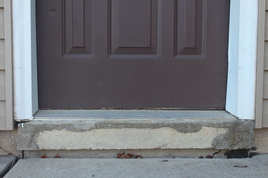A brown door with a white trim and a concrete step