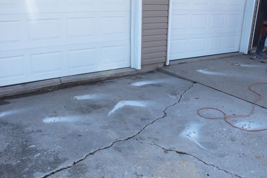 A cracked concrete driveway in front of a garage door.