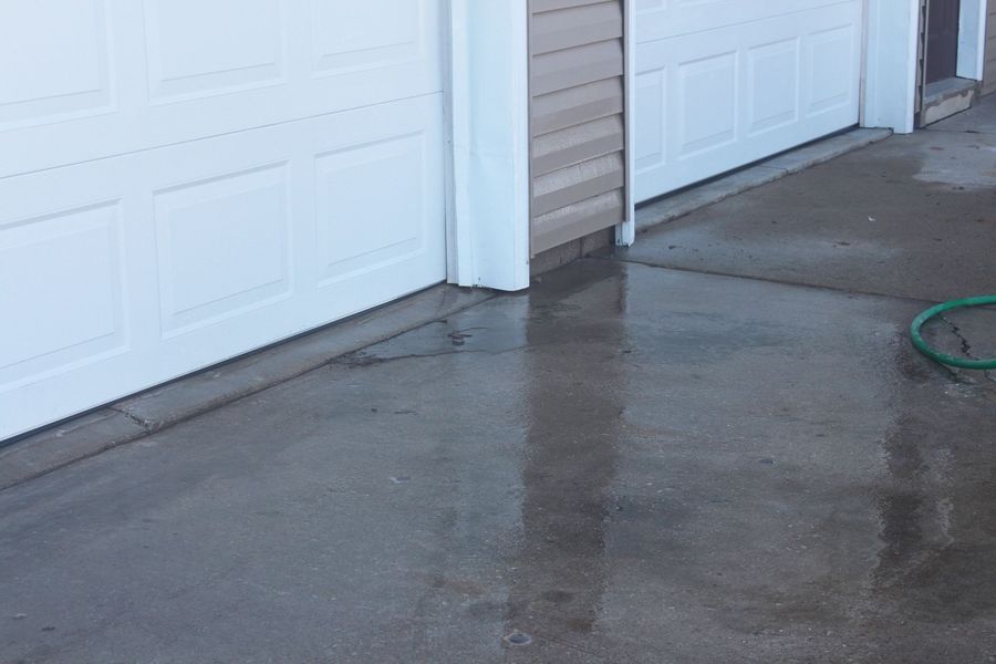A hose is sitting on the ground in front of a garage door.