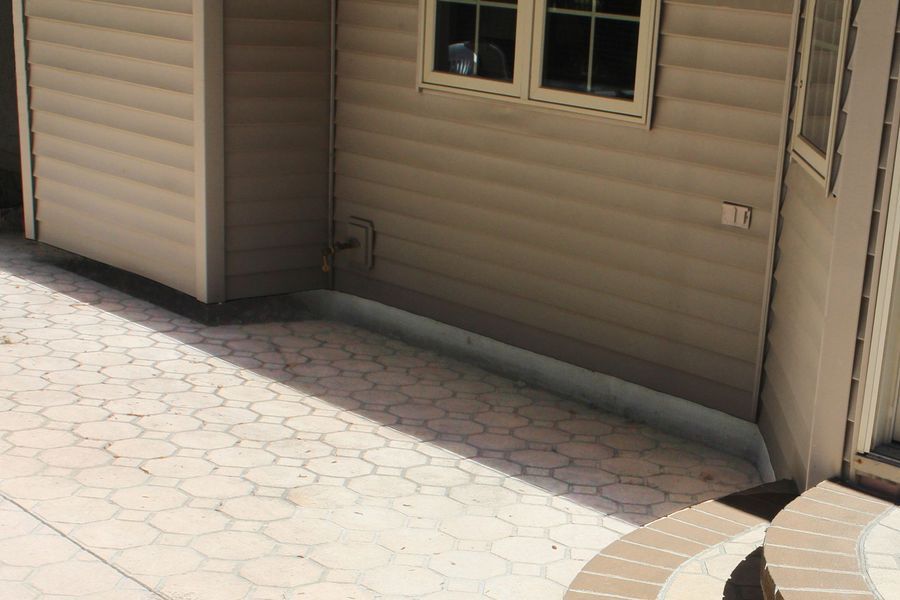 A house with a shed and a patio in front of it.