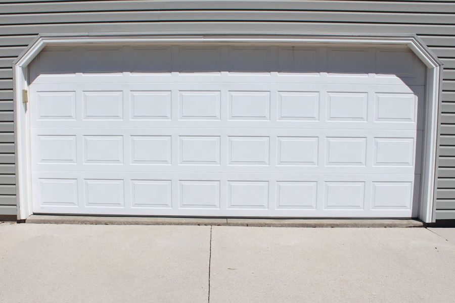 A white garage door is sitting on the side of a house.
