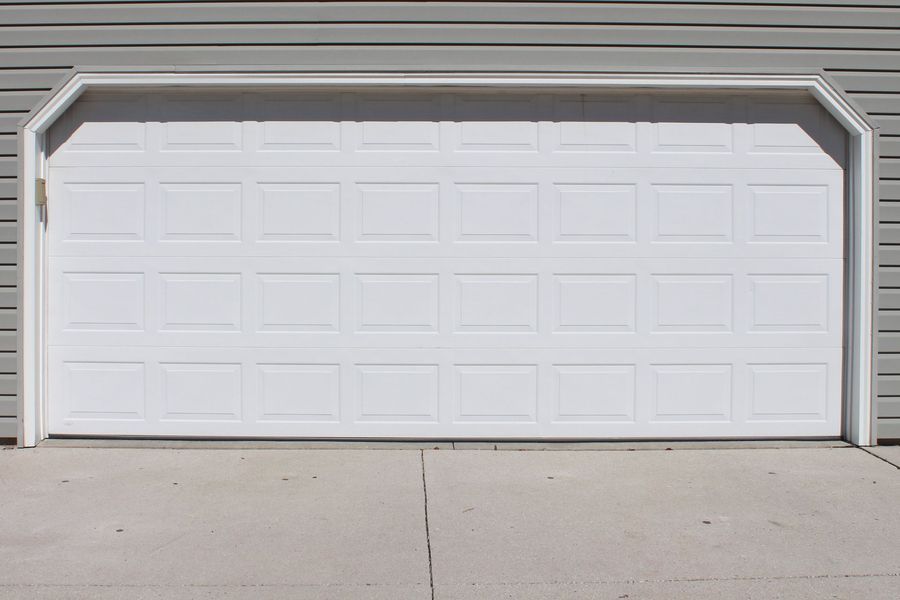 A white garage door is open on the side of a house.