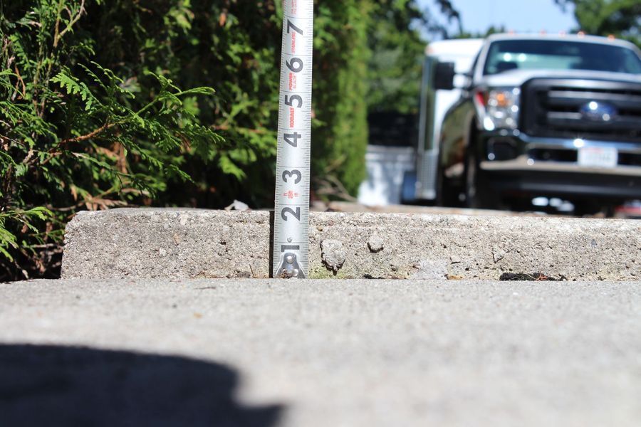 A white truck is parked on the side of the road next to a measuring stick.