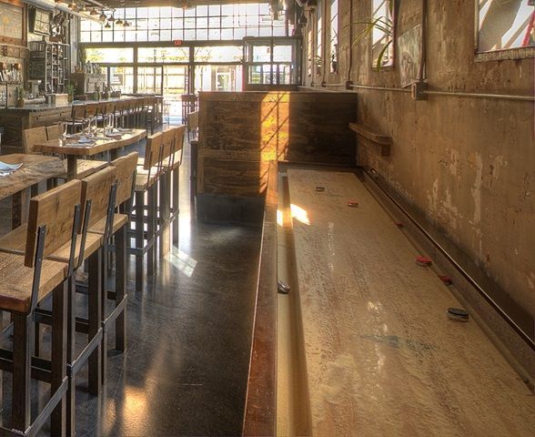 A long room with tables and chairs and a bowling alley