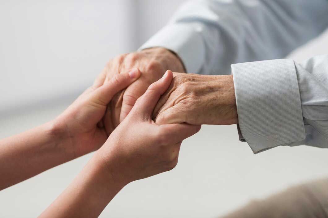 A woman is holding the hand of an older man.
