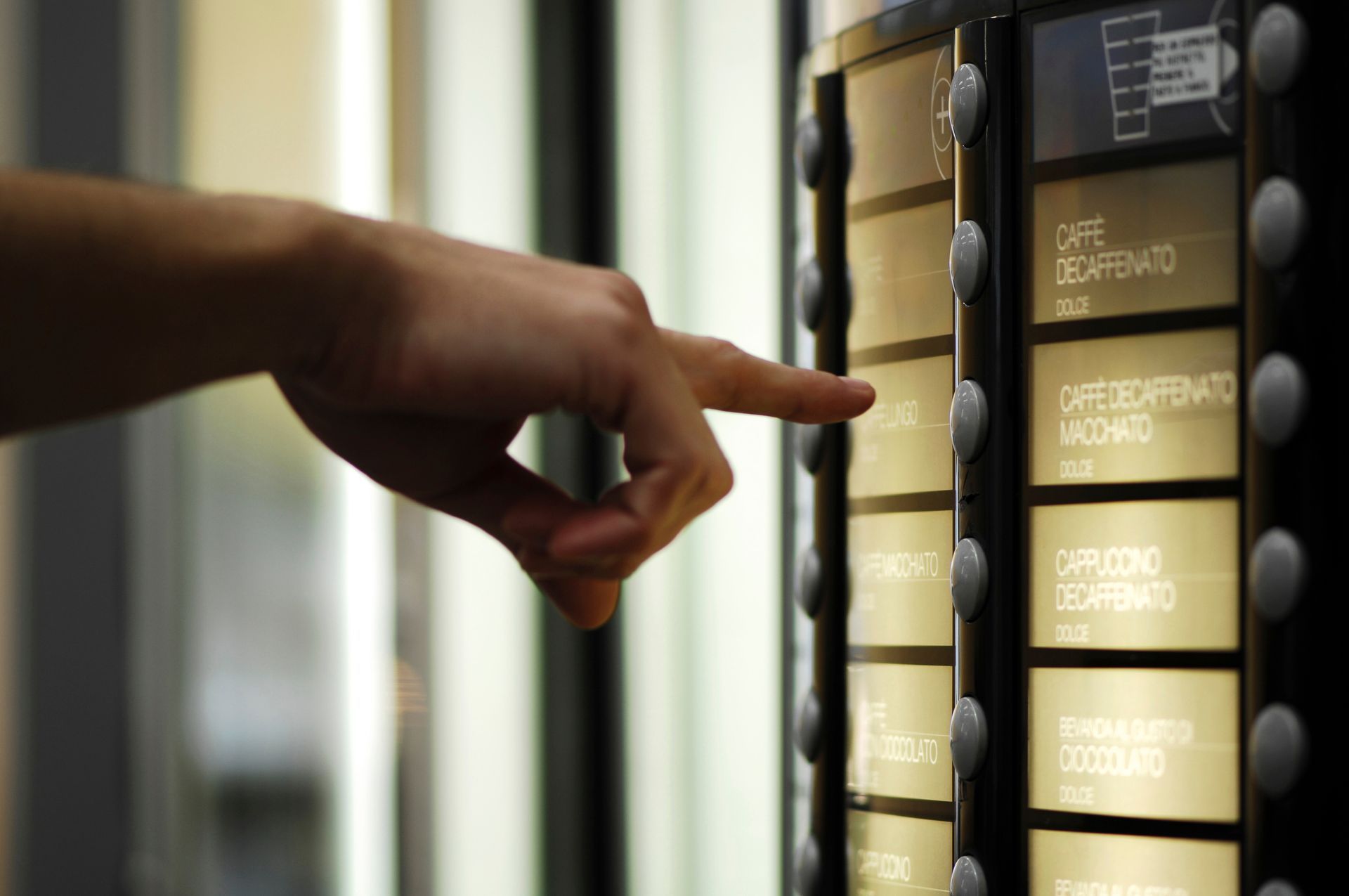 Hand pointing at a lit directory panel with names in a building lobby