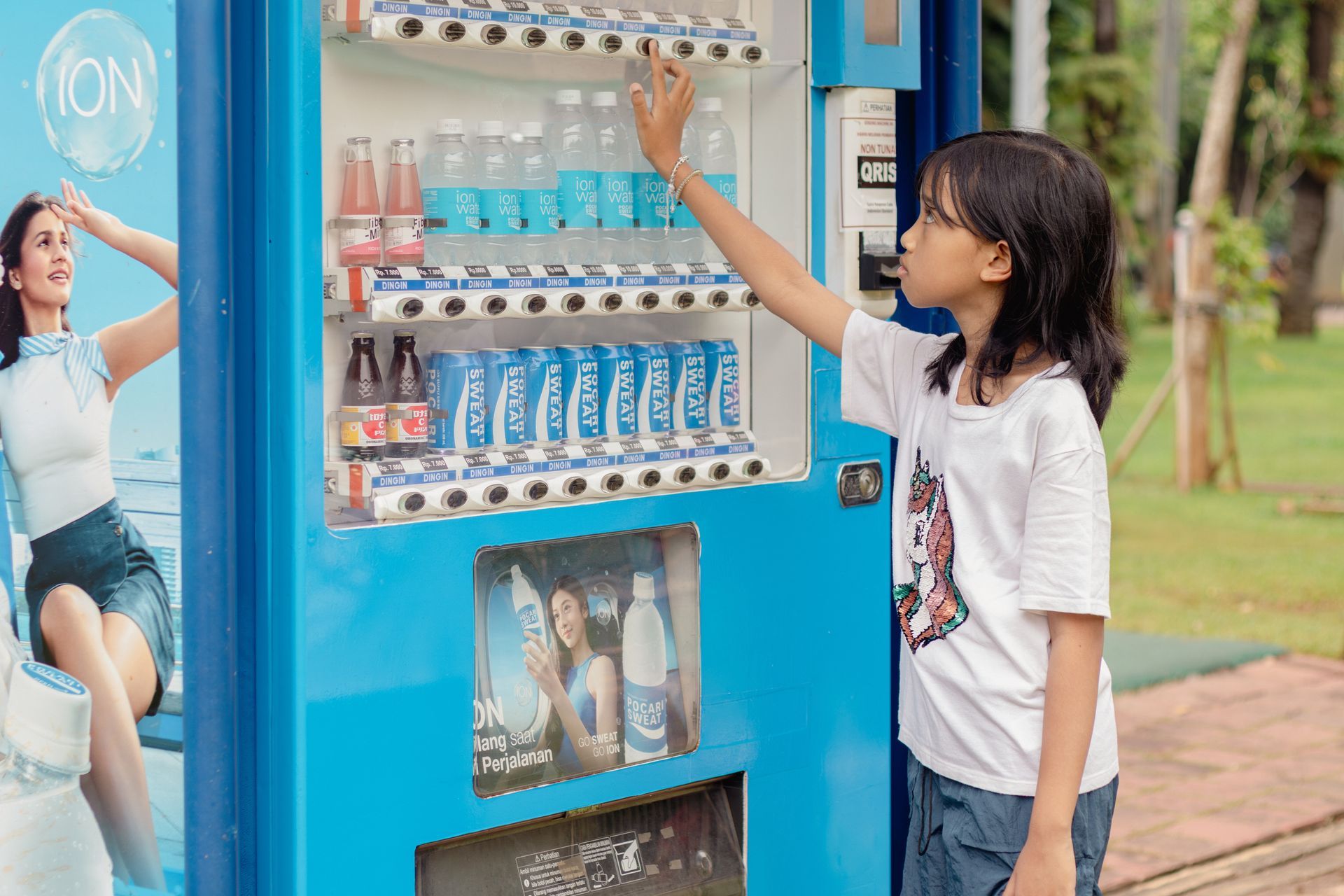Girl reaching for a drink at a blue vending machine outdoors