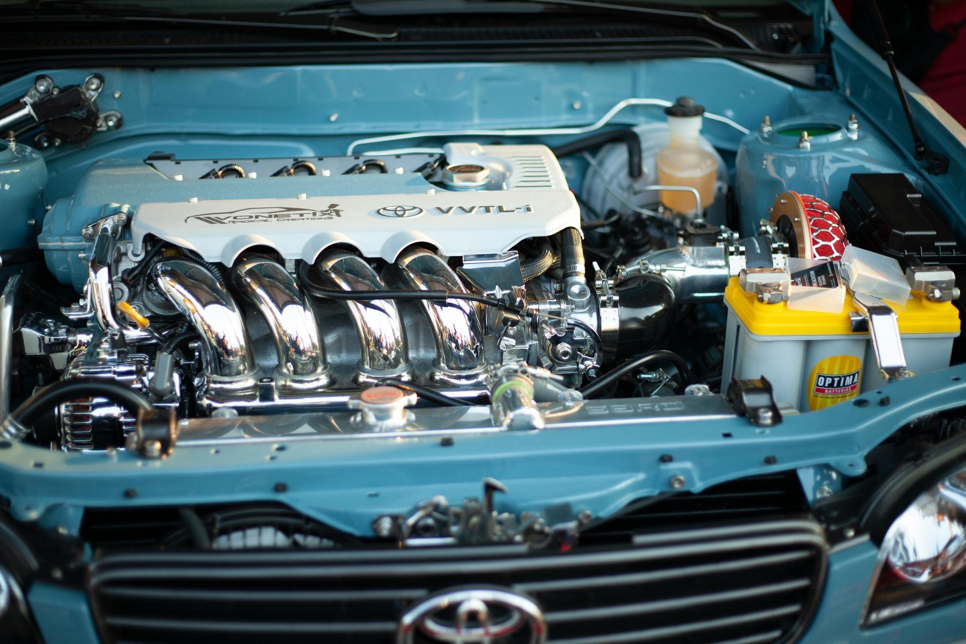 The engine of a blue toyota is shown with the hood open. Jado Mobile Auto Repair