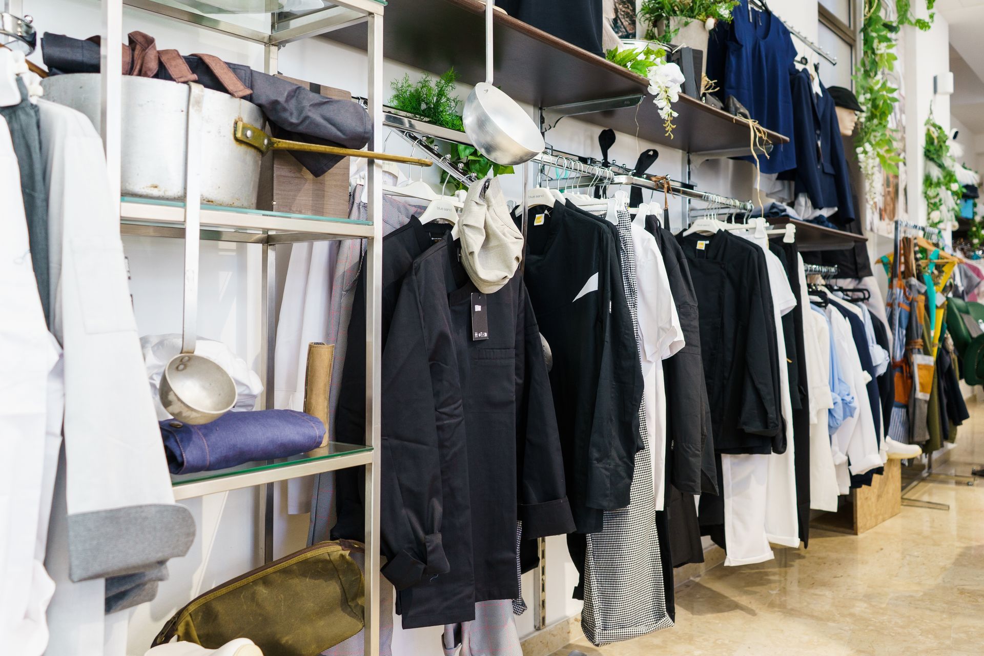 Interno di un negozio di abbigliamento con scaffali pieni di vestiti e scaffali con accessori.
