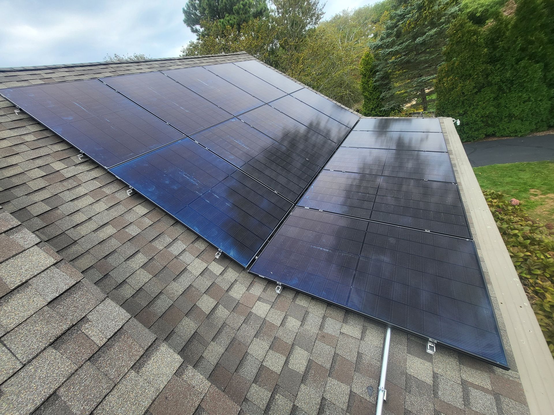 Solar pool heating panels installed on a residential shingled roof, showing dark, coiled tubing patterns.
