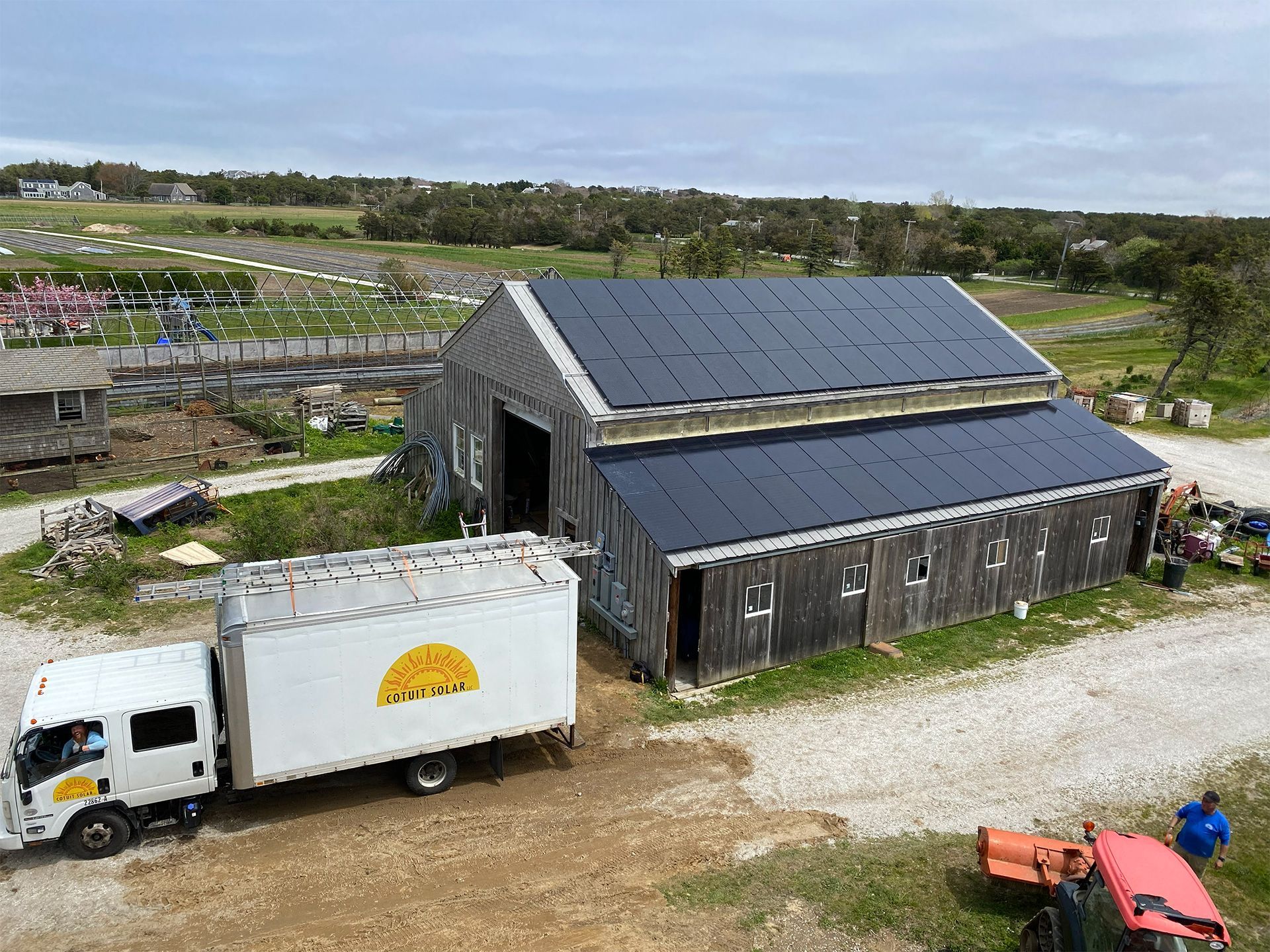 Solar panels covering the sloped roof of a historic red brick building with large arched windows.