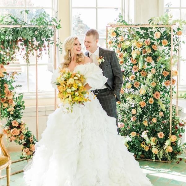 Bride and groom posing with bouquet in a bright floral wedding venue