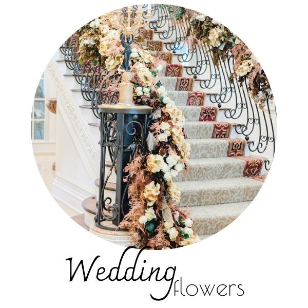 Wedding flowers cascading down a staircase with ornate black railings and pastel floral arrangements