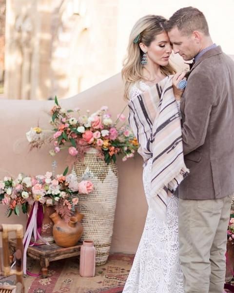 Couple standing close beside floral arrangements and decor in a soft, romantic indoor setting