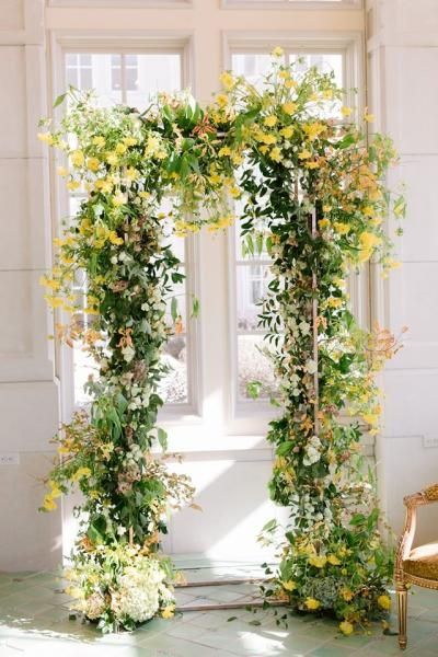 Flower-covered archway with white and yellow blossoms in a bright indoor setting