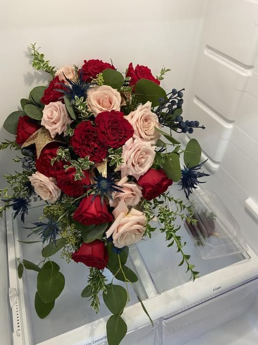 Bouquet of red, blush, and cream roses with greenery on a white chair near a door