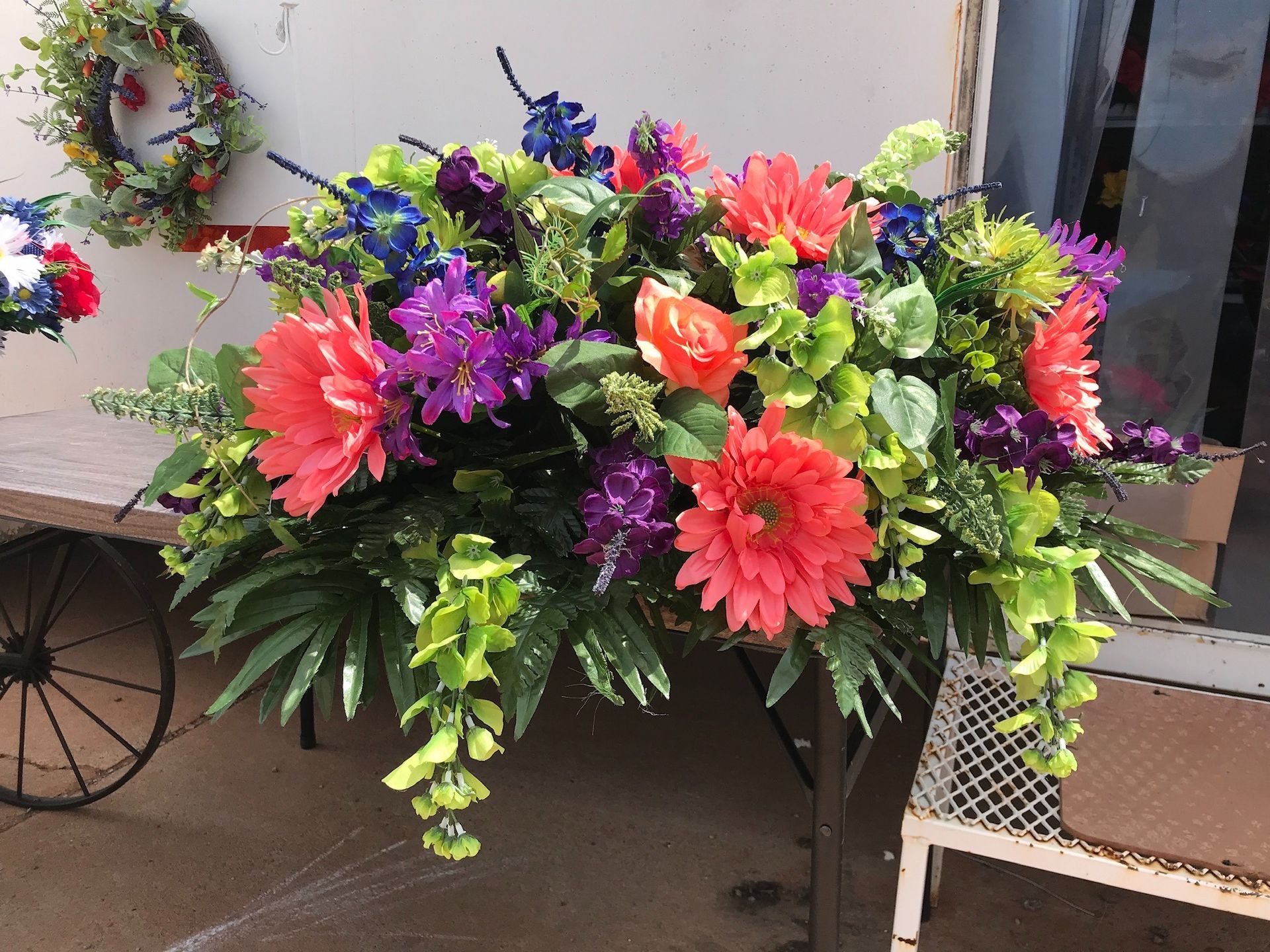 Colorful flower arrangement with pink, purple, yellow, and green blooms on a decorative cart outdoors