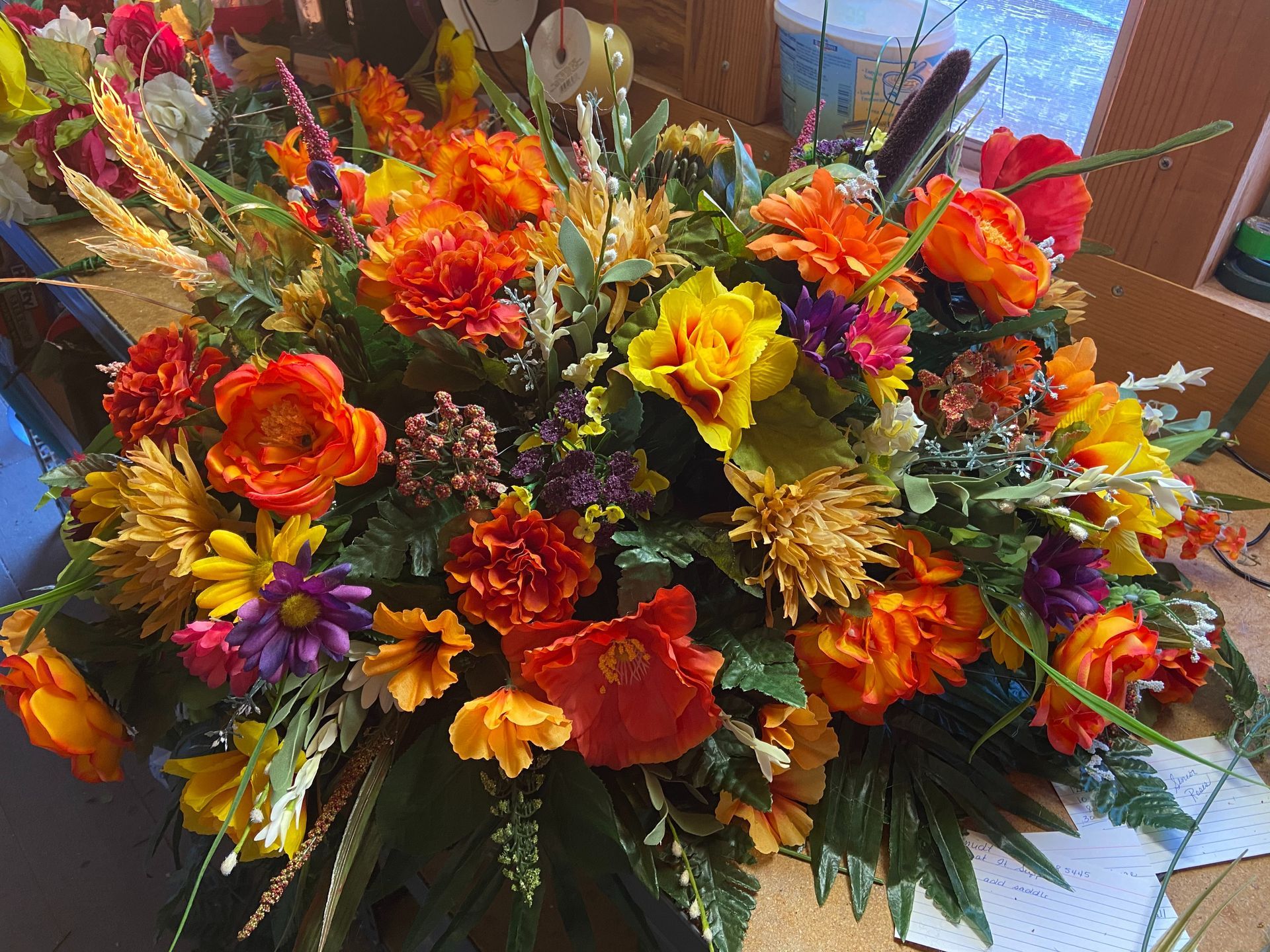 Colorful mixed flower bouquet with orange, yellow, red, and purple blooms in a vase outdoors